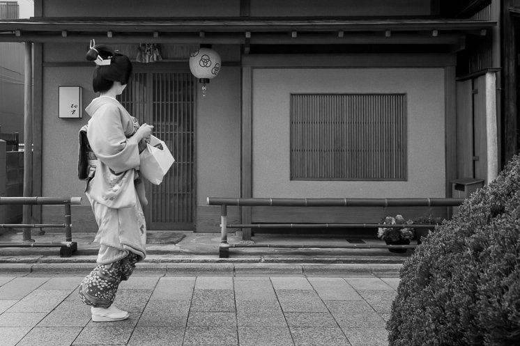 A geisha passes by a traditional house in Miyagawa-chō, Kyōto.