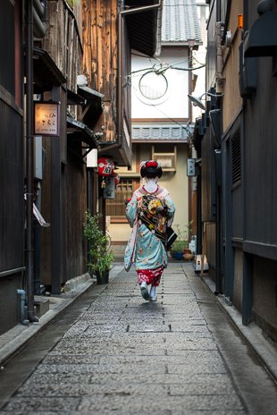 A geisha walking through one of the smaller side streets of Gion, Kyōto.