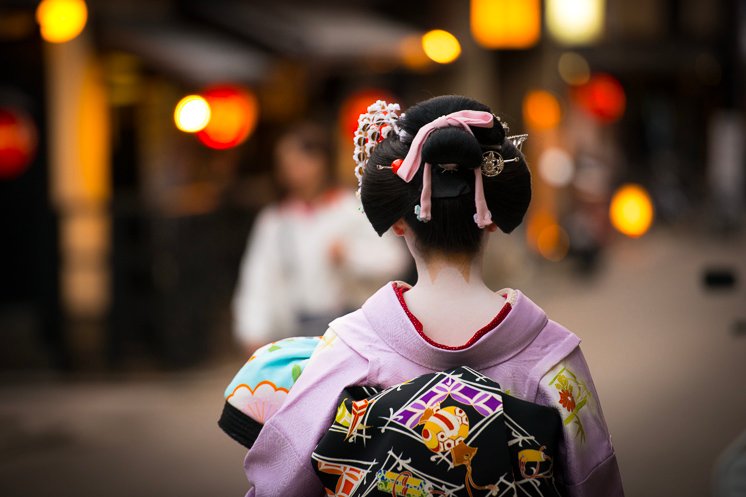 A geisha walking through Gion at night.